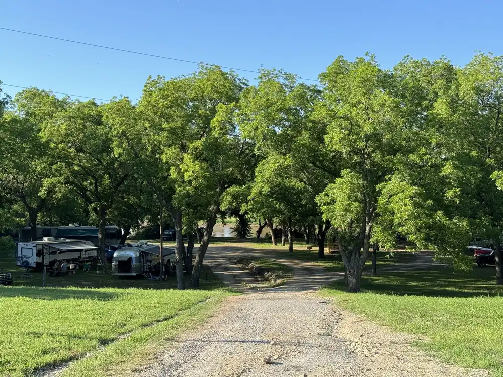 Tree-lined entrance to Rivershire RV Resort in summer